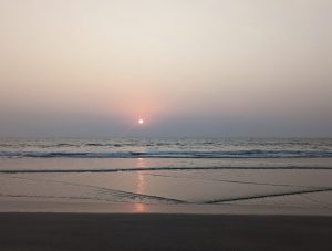 intensely red sun over a serene beach