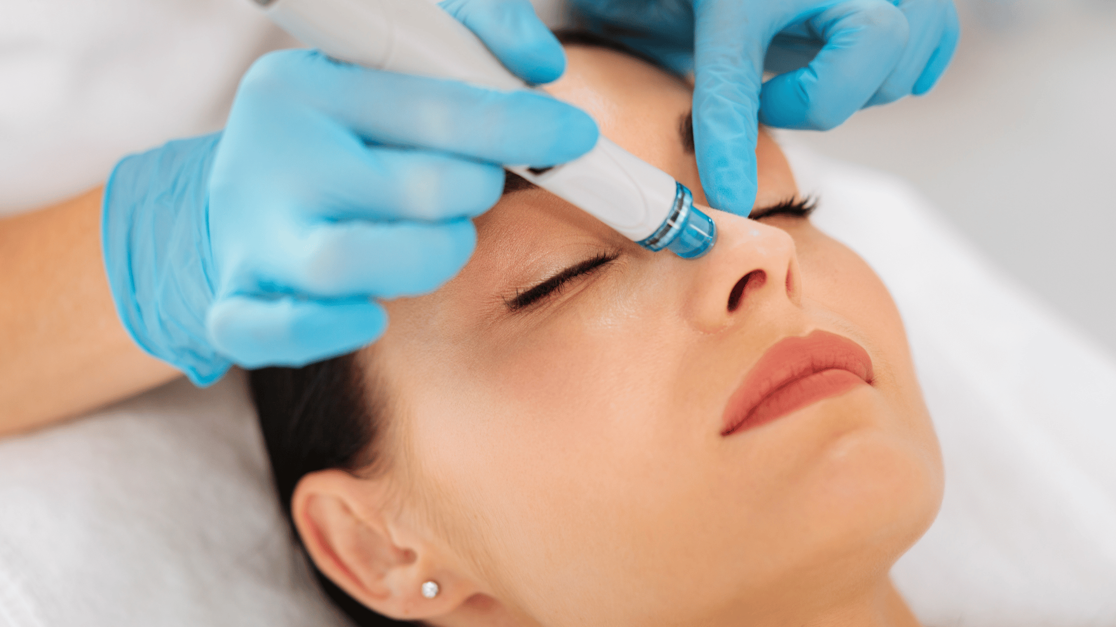 a woman receives a medical facial. The image shows a close up of the facial device on the womans face. She is relaxed and serene.