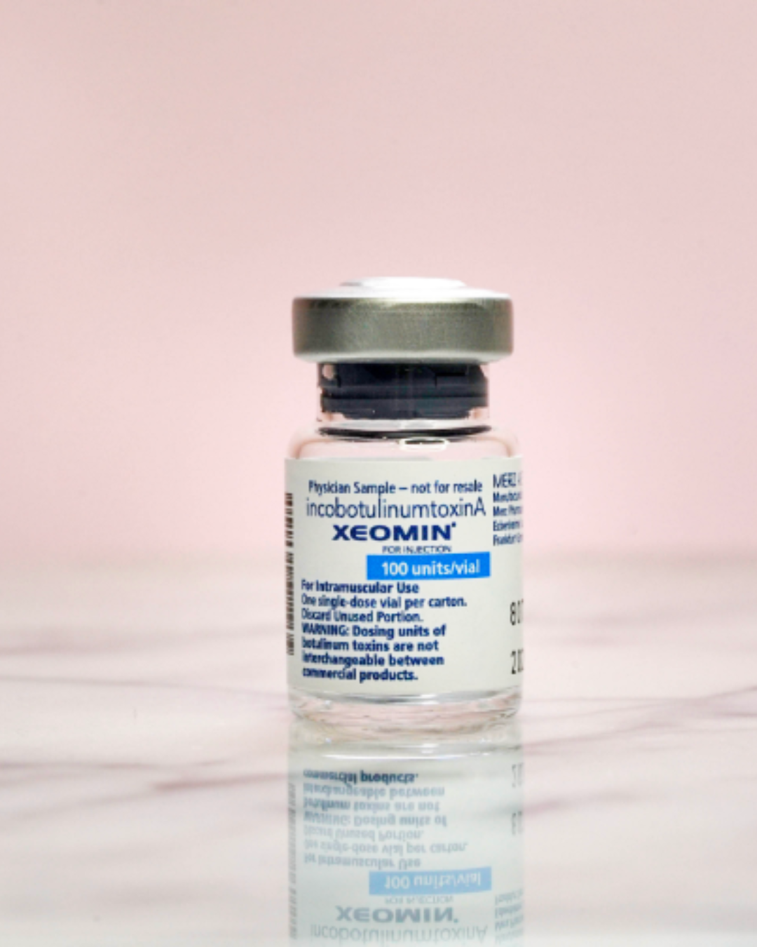 A vial of xeomin on a marble surface. The background is light pink.