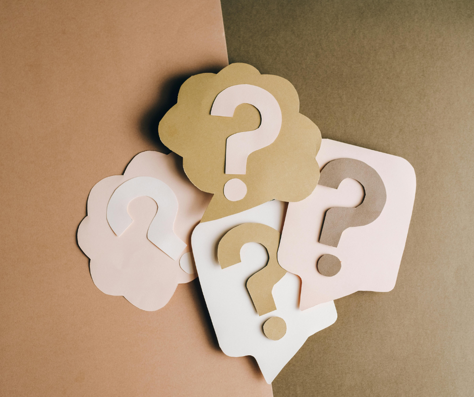 question marks cut out of paper and piled together. The paper is all skin tones in color.